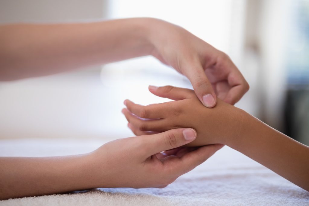 Close-up of female therapist examining hand on white towel